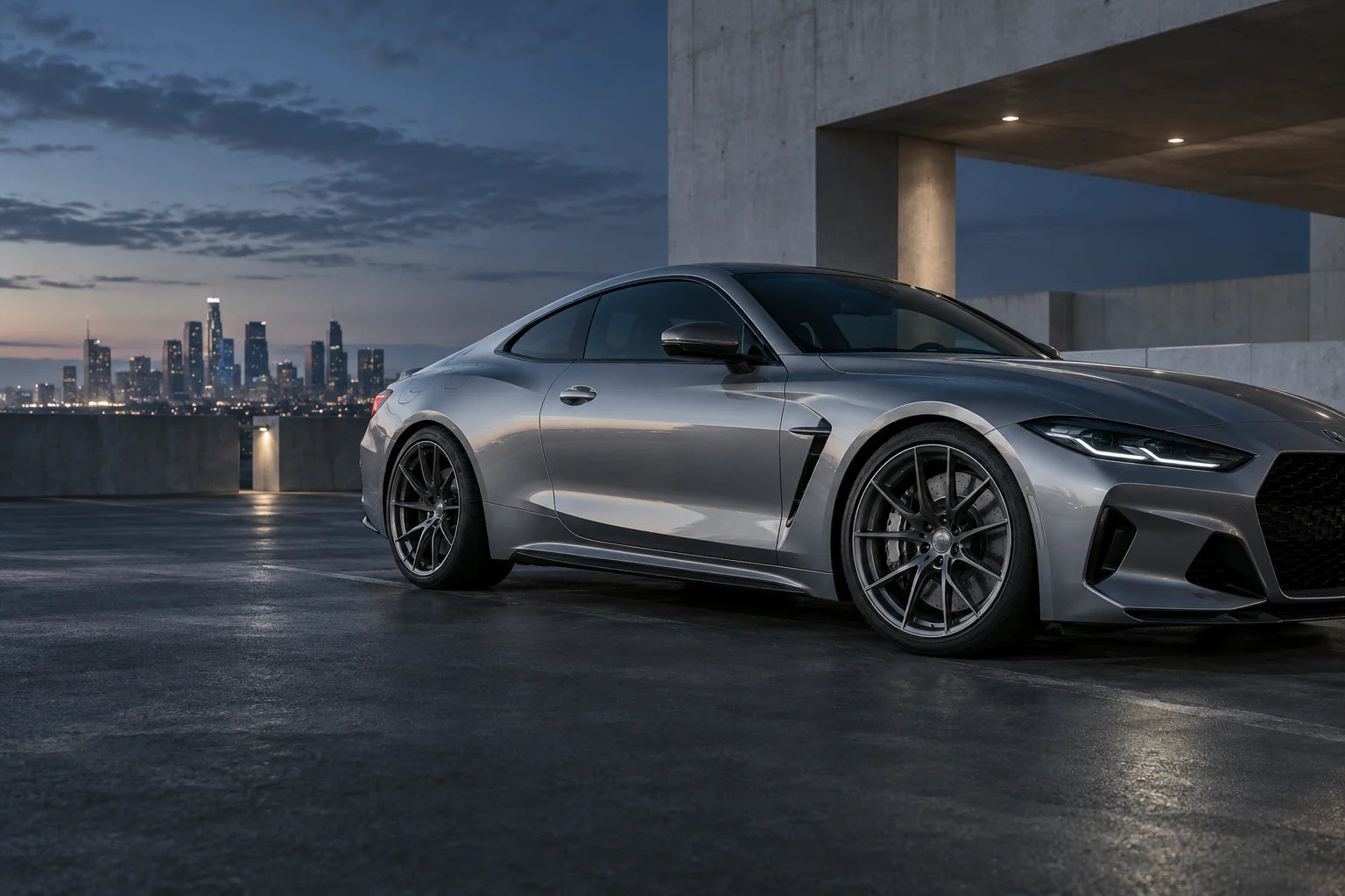 Silver performance coupe with gunmetal multi-spoke wheels on a rooftop at dusk